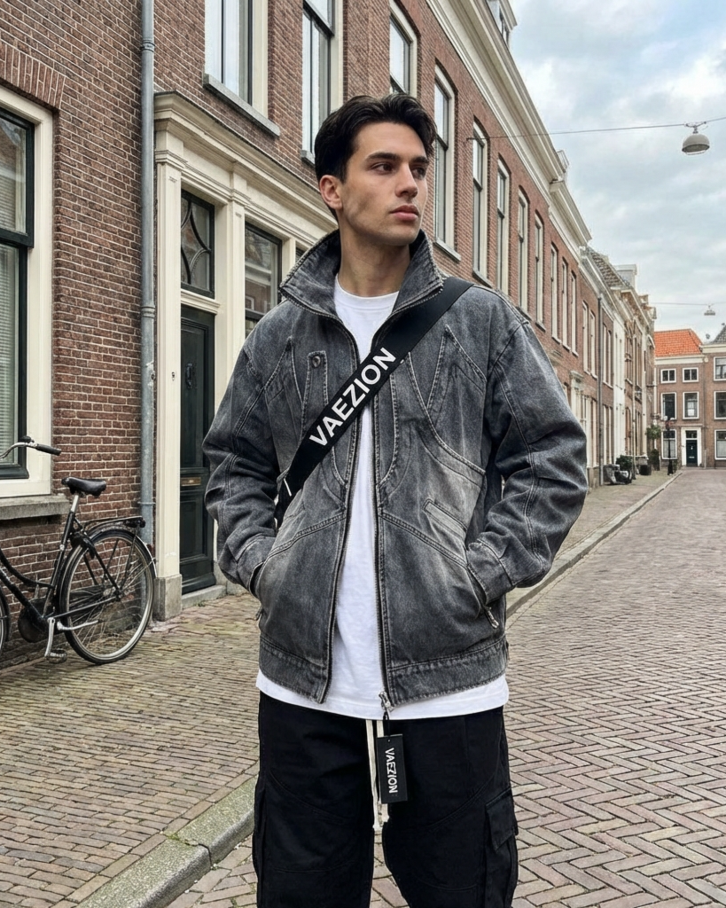 Man in streetwear jacket and cargo pants with VAEZION strap, posing on city street