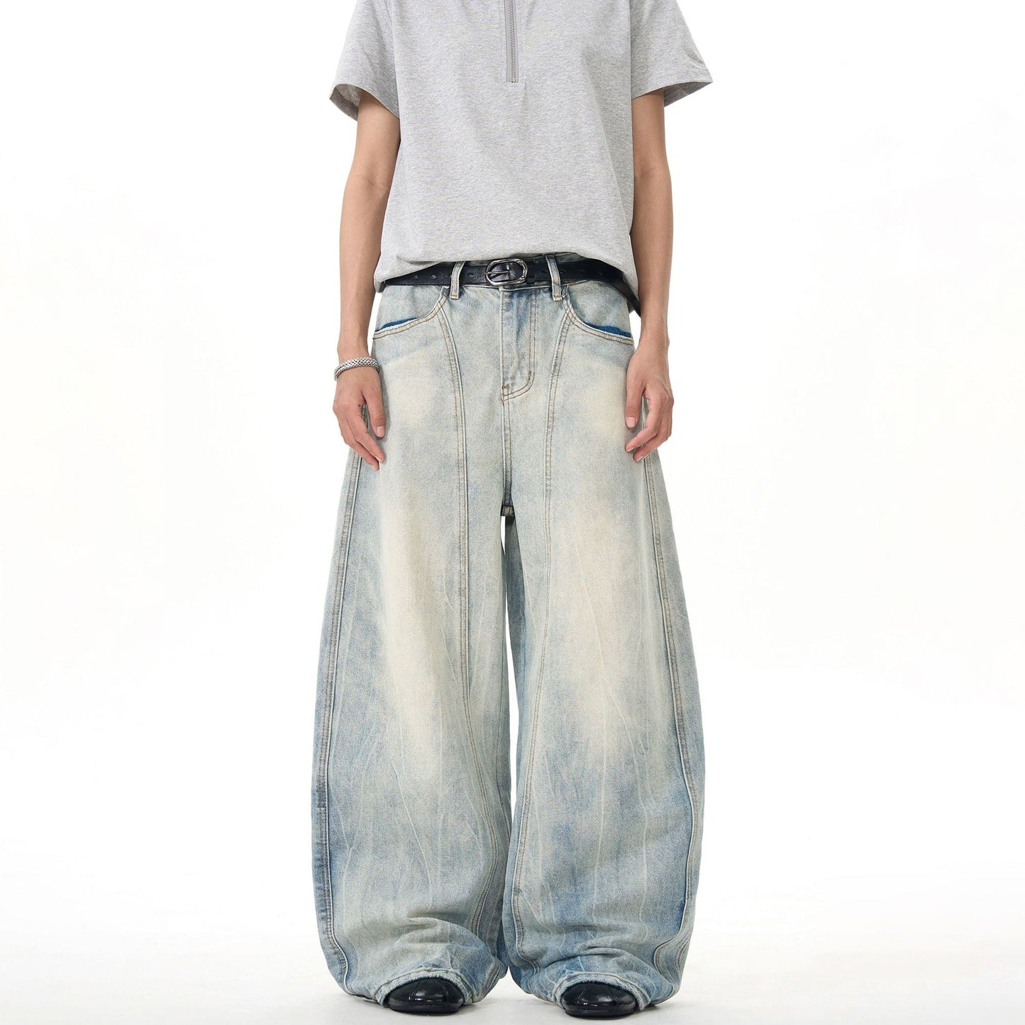 Man wearing oversized wide-leg faded denim jeans and a light gray T-shirt, Vaezion streetwear style