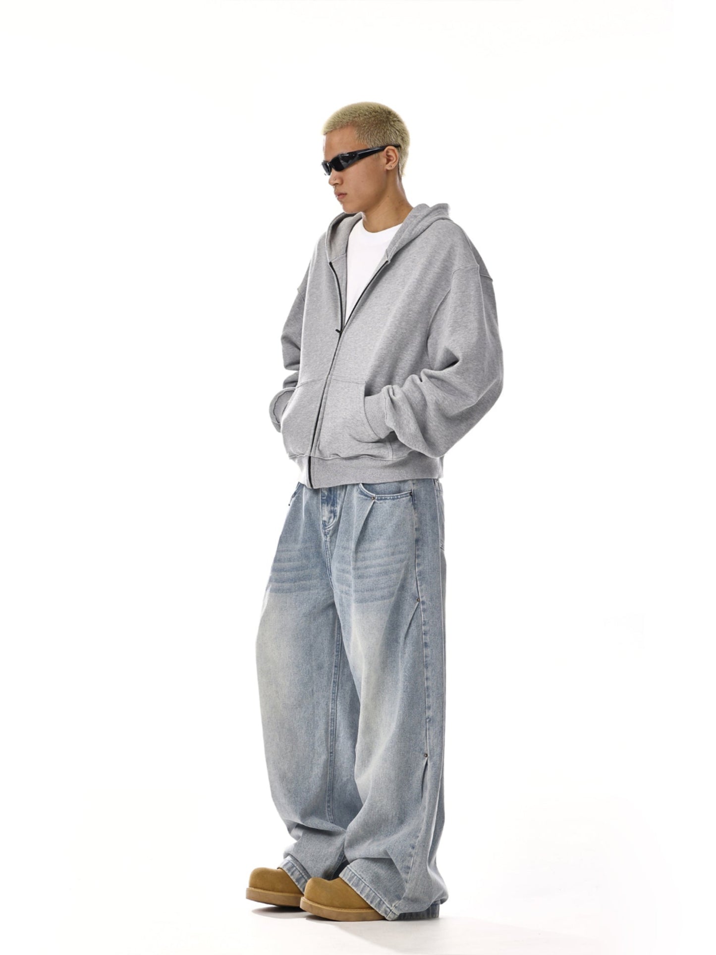 Streetwear model in grey hoodie, baggy light wash jeans, and sunglasses for Vaezion Shop