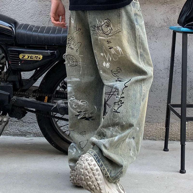 Streetwear denim jeans with graffiti print next to motorcycle, Vaezion Shop fashion