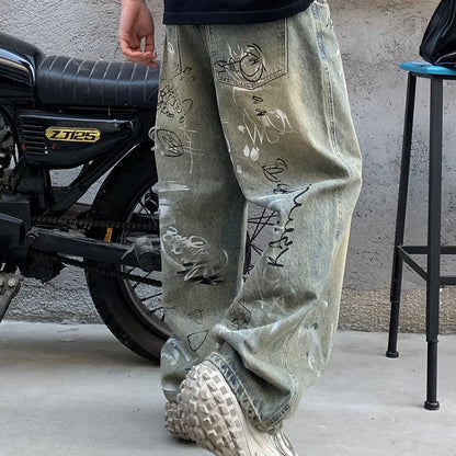 Streetwear denim jeans with graffiti print next to motorcycle, Vaezion Shop fashion