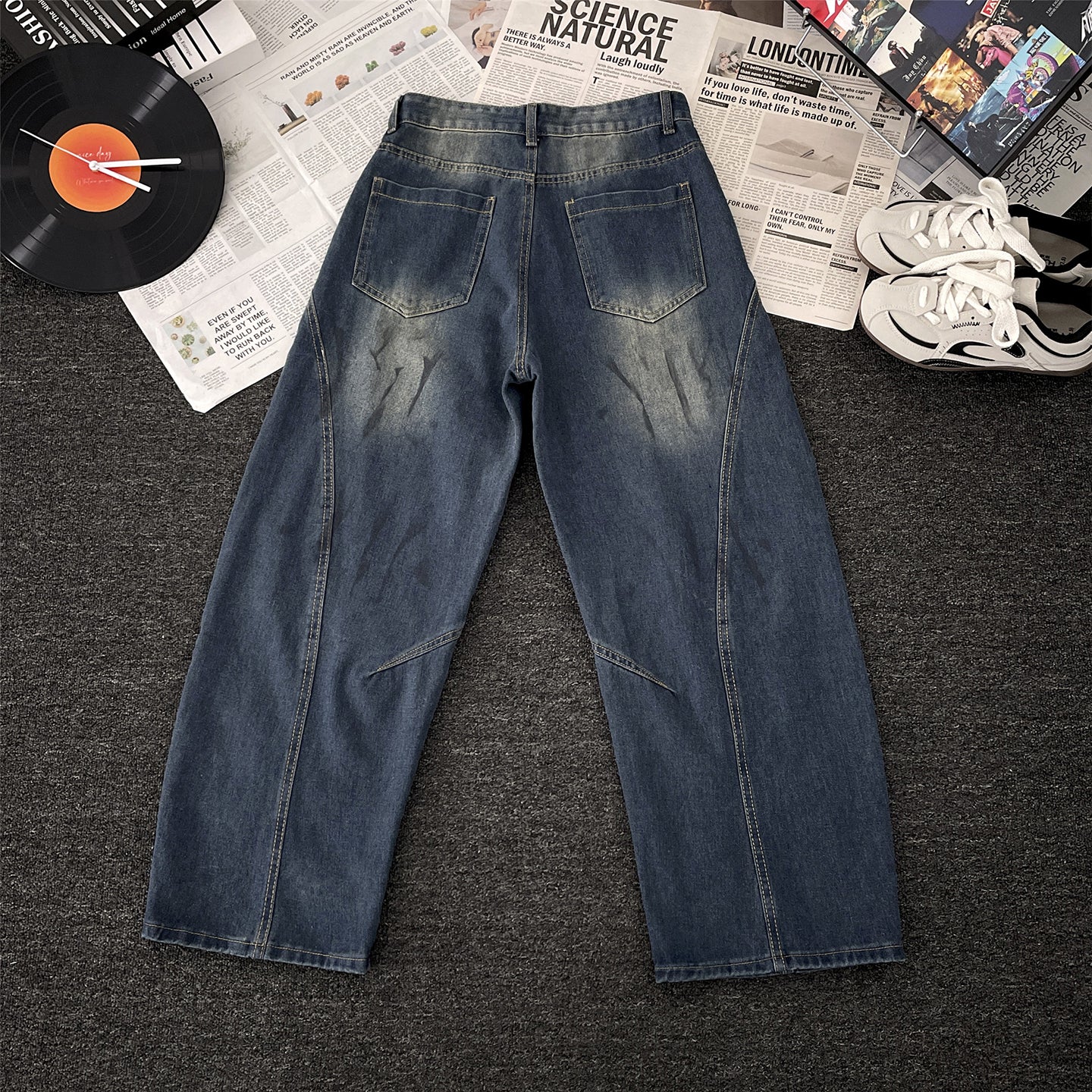 Vaezion Shop street style men's loose fit denim jeans with back pockets, laid on carpet with sneakers, vinyl record, and magazines.