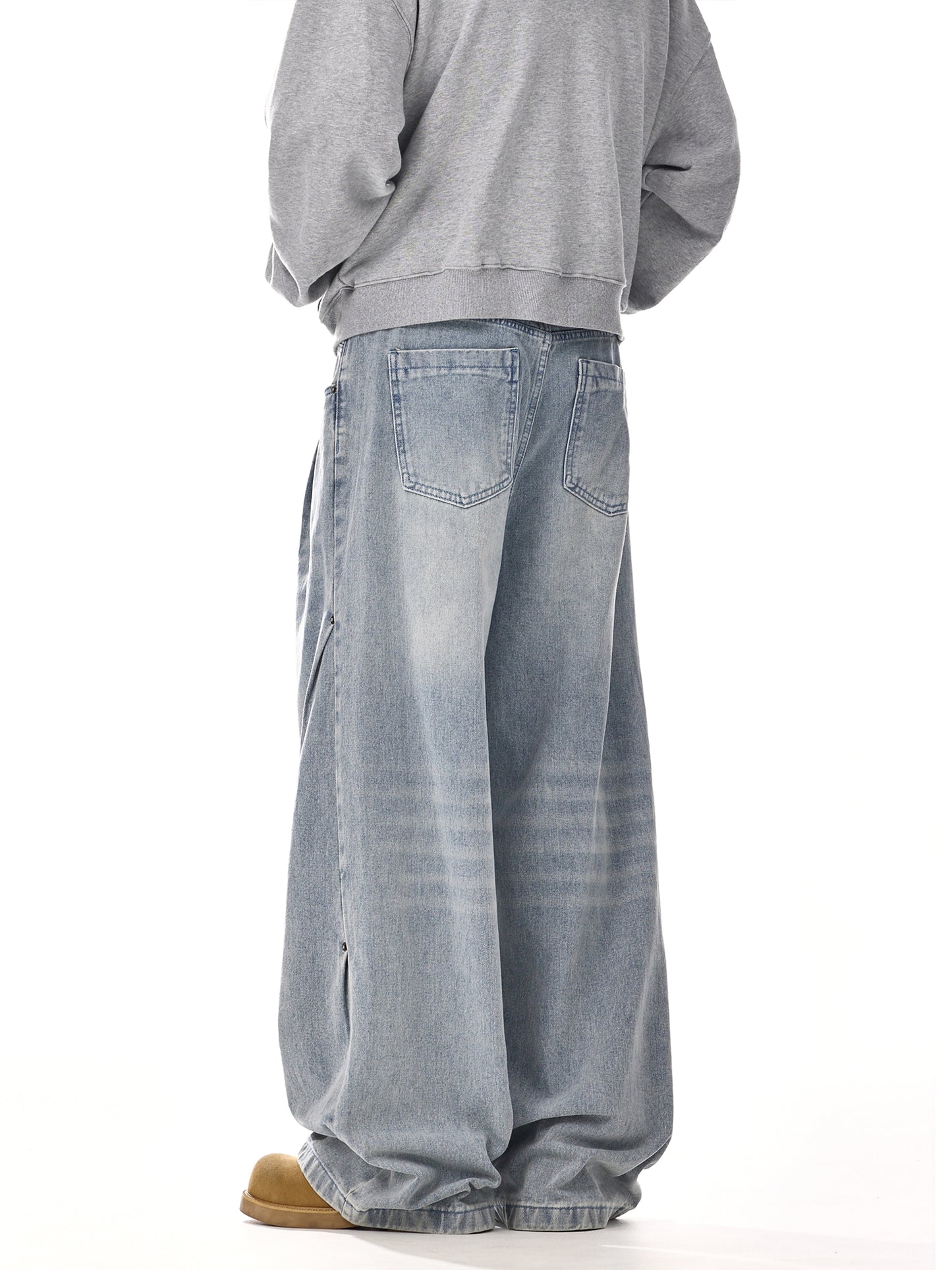 Man wearing oversized light wash jeans and a grey sweatshirt, streetwear fashion